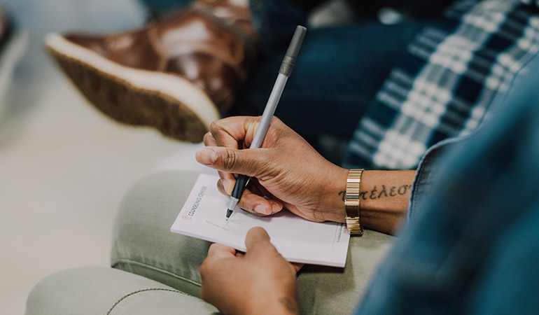 a man writing notes in a group session at Middlesex